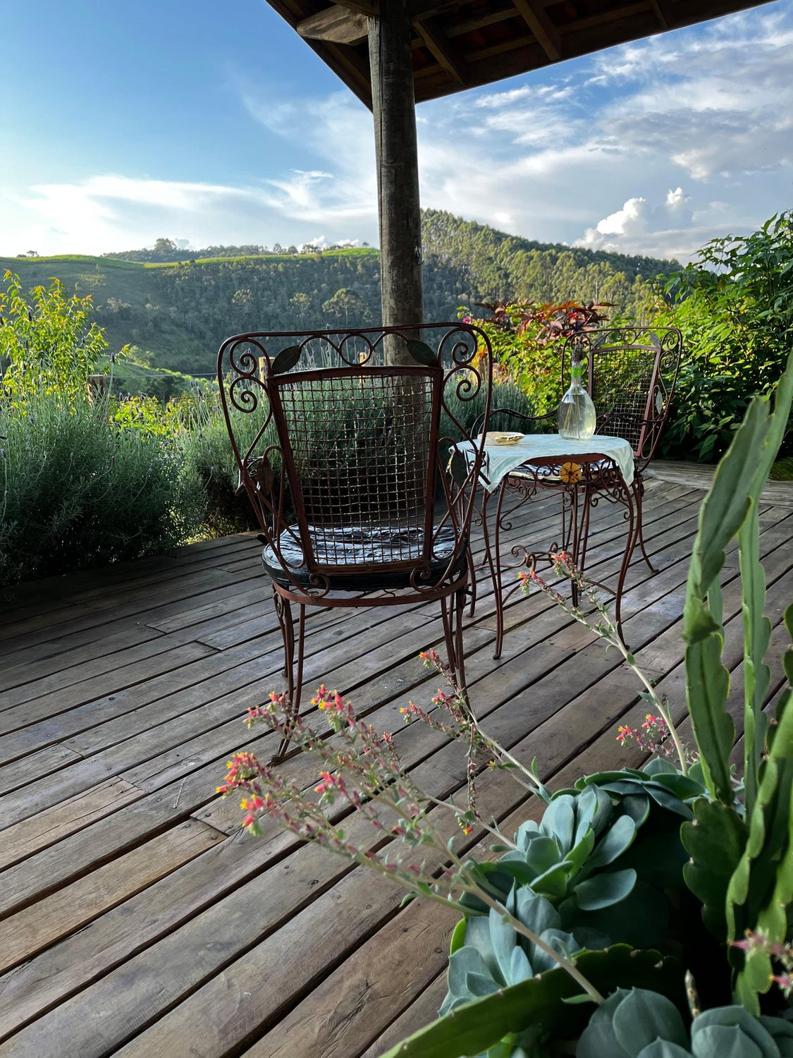 Deck de madeira da varanda com cadeiras e vista para os morros da Serra da Mantiqueira